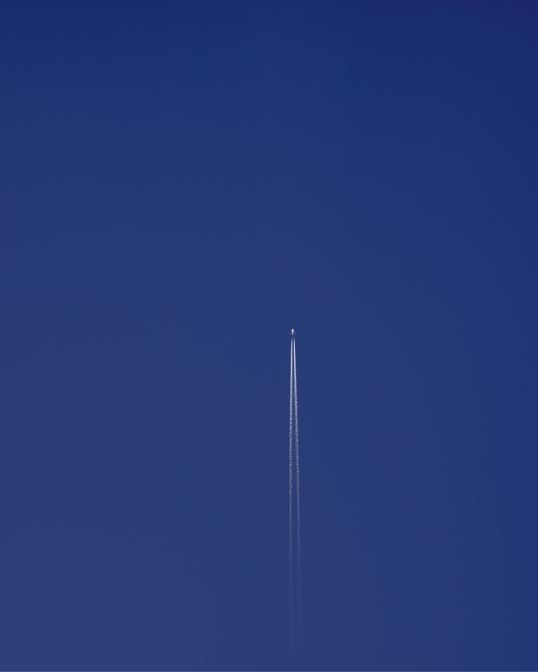 Aircraft at cruise leaving a contrail in a deep blue sky